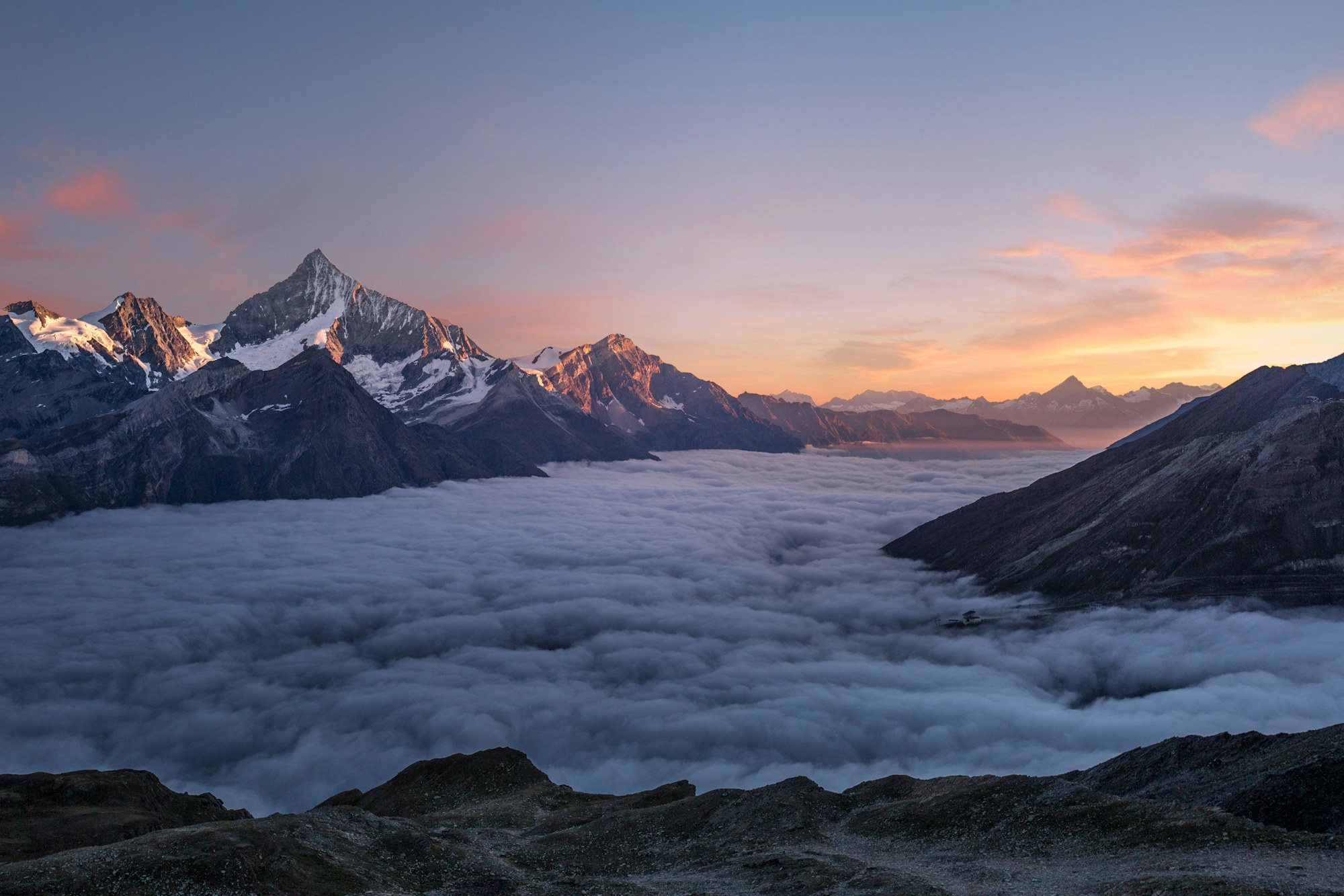 Vast alpine landscape at dawn, a lone figure dwarfed by the mountain scale